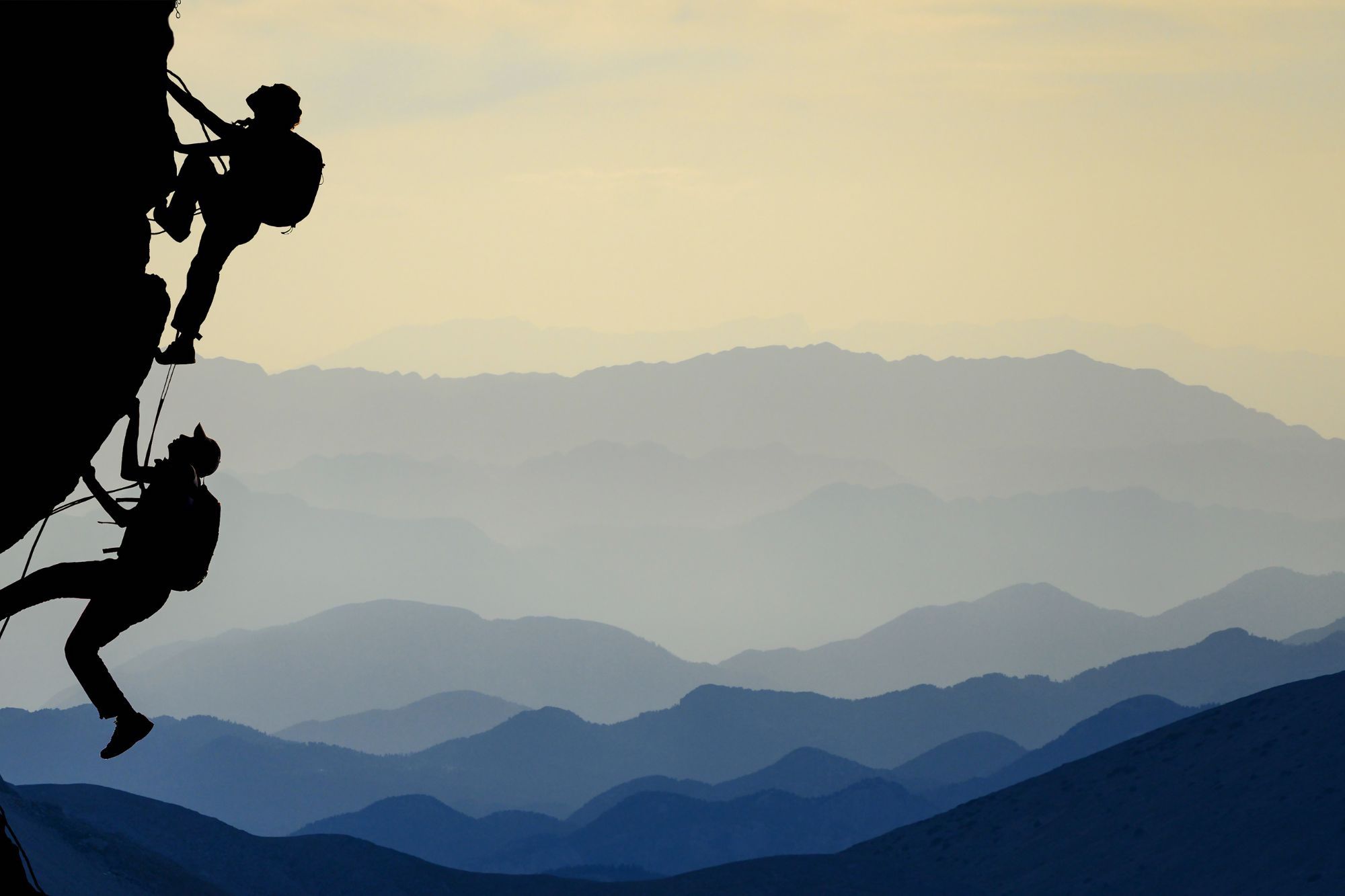 Two climbers climbing up a mountain side